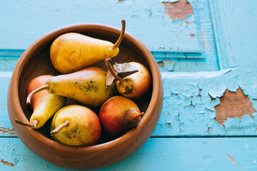 Fresh pears in a wooden plate on an old wooden blue background