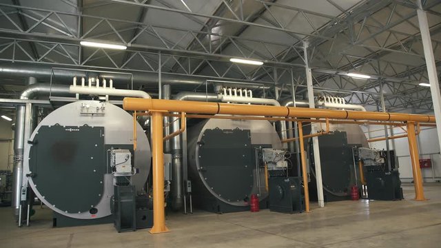 Three large gas boilers in an automated boiler house. Interior industrial with a lot of piping, pumps and valves. Modern boiler room equipment for heating system. Pipelines, water pump