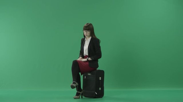 Young business woman sits on her suitcase waiting for the departure
