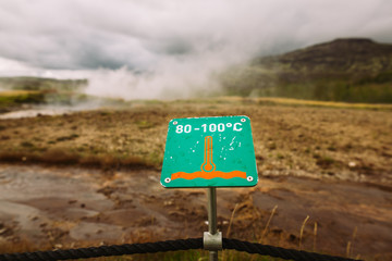 Warning sign of hot earth.Caution of high temperature on golden circle tour near big geyser geothermal area.Steaming boiling water and ground.Tourist attraction of watching geyser erupting in Iceland