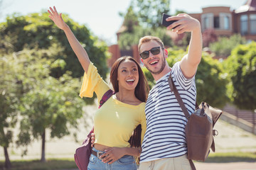 Obraz premium young happy multiethnic couple gesturing and taking selfie on smartphone