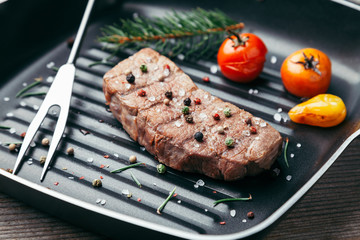 Delicious grilled steak with seasoning on wooden background