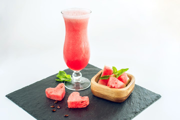 Fresh red smoothie in a glass with sliced pieces of watermelon and mint on white isolated background. Summer cool drinks