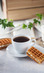 Cup of coffee and Belgian waffles with cream for breakfast
