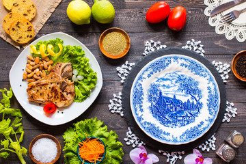 Pork steak homemade cooking with spices leaves lettuce on wooden cutting board, and a dish,