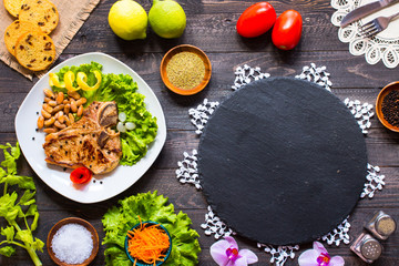 Pork steak homemade cooking with spices leaves lettuce on wooden cutting board, and a dish,