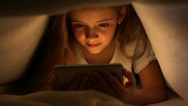 Young girl watching online content on her smartphone at night
