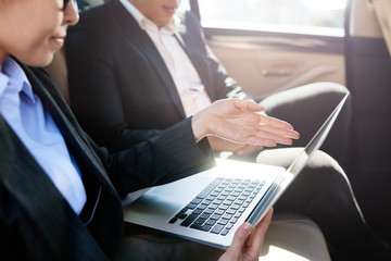 Serious man and woman discussing in a car with laptop