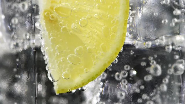 Macro close up slice lemon, ice cubes and bubble float soda water, UHD 4k 3840x2160.
