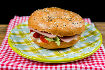Bagel with fresh cheese and fresh lettuce on napkin
