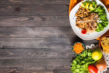 Pork steak homemade cooking with spices leaves lettuce on wooden cutting board, and a dish,