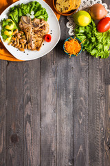 Pork steak homemade cooking with spices leaves lettuce on wooden cutting board, and a dish,