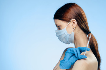 Young beautiful woman on a blue background holds a syringe, medicine, plastic surgery