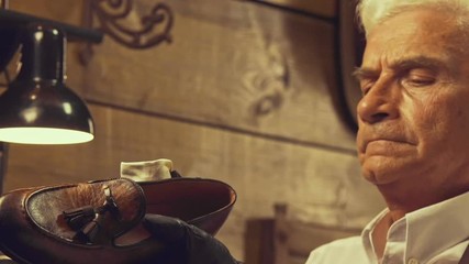 Senior cobbler man polishes a leather shoe at his workshop
