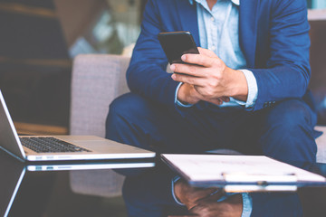 Handsome businessman in suit and eyeglasses speaking on the phone in office,Side view shot of a man's hands using smart phone in rear view of business man busy using cell phone at office.