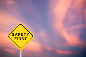 Safety first wording on yellow transportation sign with violet cloud sky background