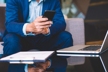 Handsome businessman in suit and eyeglasses speaking on the phone in office,Side view shot of a man's hands using smart phone in rear view of business man busy using cell phone at office.