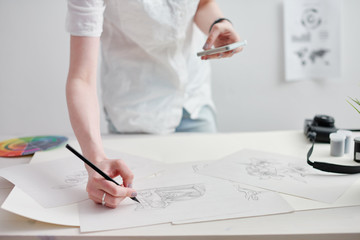 Young female illustrator working on sketches at home office