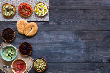Italian bruschetta with cheese, tomato sauce, cucumber sauce, and herbs, on a wooden background.