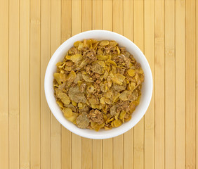 Top view of multigrain breakfast cereal in a white bowl on a wood place mat.