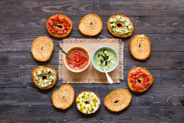 Italian bruschetta with cheese, tomato sauce, cucumber sauce, and herbs, on a wooden background.