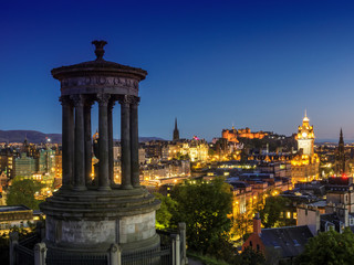 Edinburgh cityscape at night with the Dugald Stewart memorial in the foreground on Calton Hill, Scotland, UK