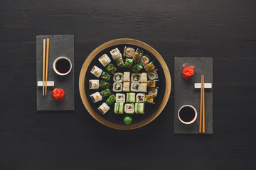 Set of sushi maki and rolls on black rustic wood, top view