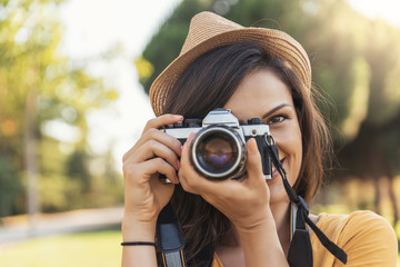 Smiling young woman using a camera to take photo.