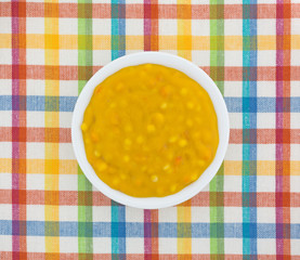 Macaroni and cheese baby food in a bowl on top of a colorful cloth place mat.