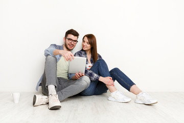 Fototapeta na wymiar Couple shopping online, sitting on floor at home