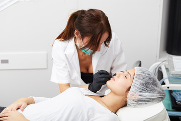 Obraz premium Cosmetologist making permanent makeup on woman's face