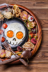 Fried eggs in the shape of a skull and fresh tomatoes. Breakfast in Halloween decorations.