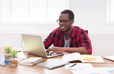 Happy black businessman in casual office, work with laptop