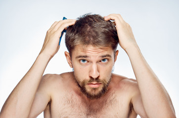 Young guy with a beard on a white isolated background holds on to his head