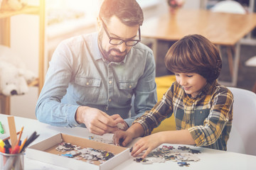 Fototapeta premium Positive nice man holding a jigsaw puzzle piece