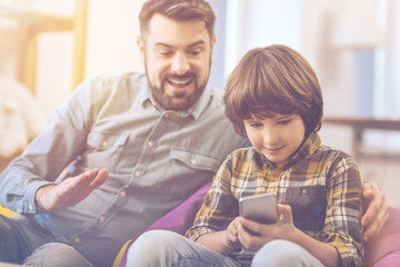 Cute joyful boy using his smartphone