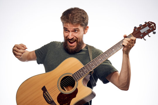 1183638 Young guy with a beard on a white isolated background holds a guitar.