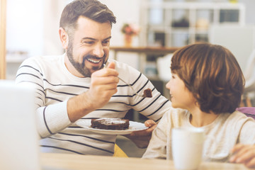 Cheerful handsome man offering his son a cake