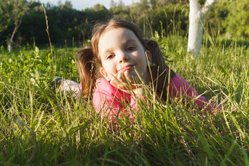 Little girl lies on the green grass in the garden