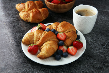 Delicious breakfast with fresh croissants and ripe berries on old marble background
