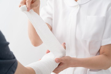 腕に包帯を巻く看護師、患者
