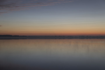 Fototapeta na wymiar Sunrise with clouds and fog over lake