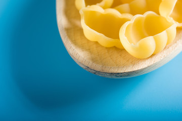 Raw Pasta on Wood Spoon in blue background