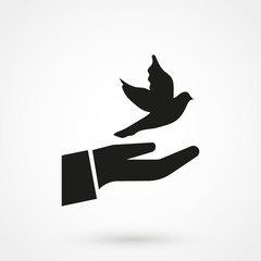 Silhouette of the human hand, which releases the bird and the bird flies