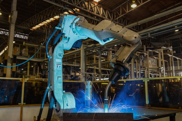 Robot is welding metal part in car factory
