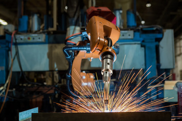 Robot is welding metal part in car factory
