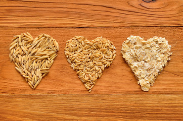 Three handfuls of raw oats, peeled oats and oat flakes on a wooden surface