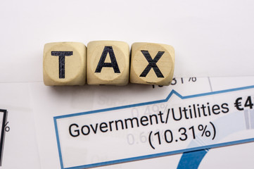 Wooden letter blocks assemble the word tax on a sheet with government tax analysis