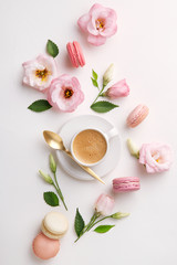 Macarons and flowers on a white background. Colorful french dessert with fresh flowers. Top view