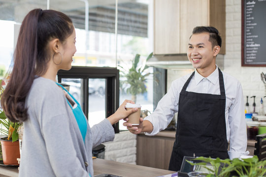 Asian barista man standing for taking order with attractive smiling at coffee shop. Man with owner business concept. 30-40 years old.